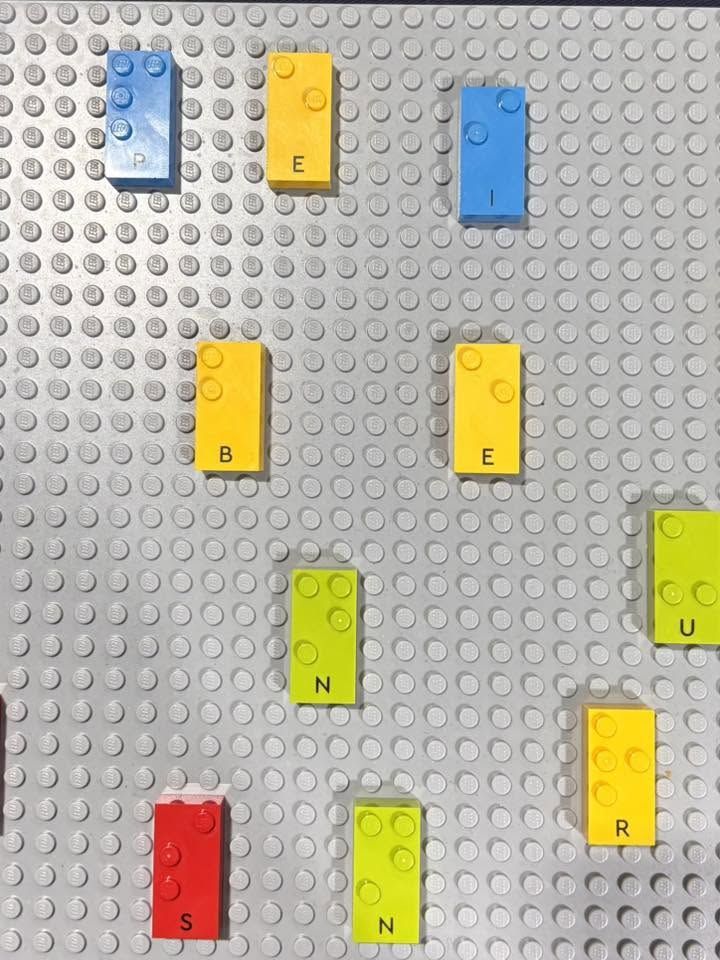Briques LEGO tactiles utilisées pour composer des lettres en braille sur une plaque de construction