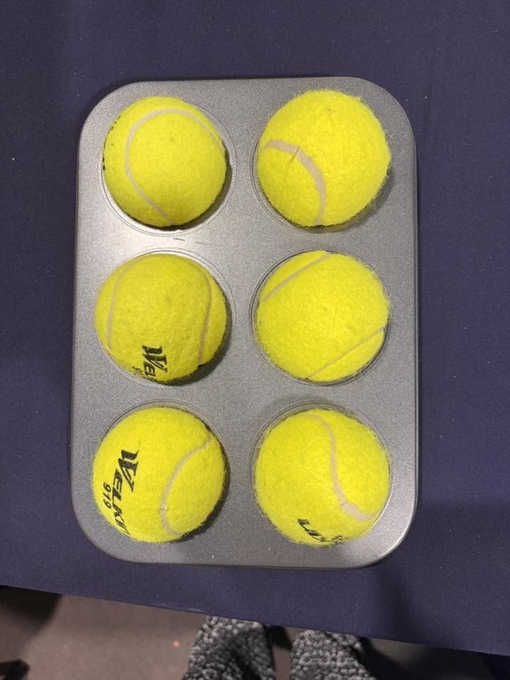 Six balles de tennis disposées dans un moule à muffins, reproduisant la disposition d'une cellule braille